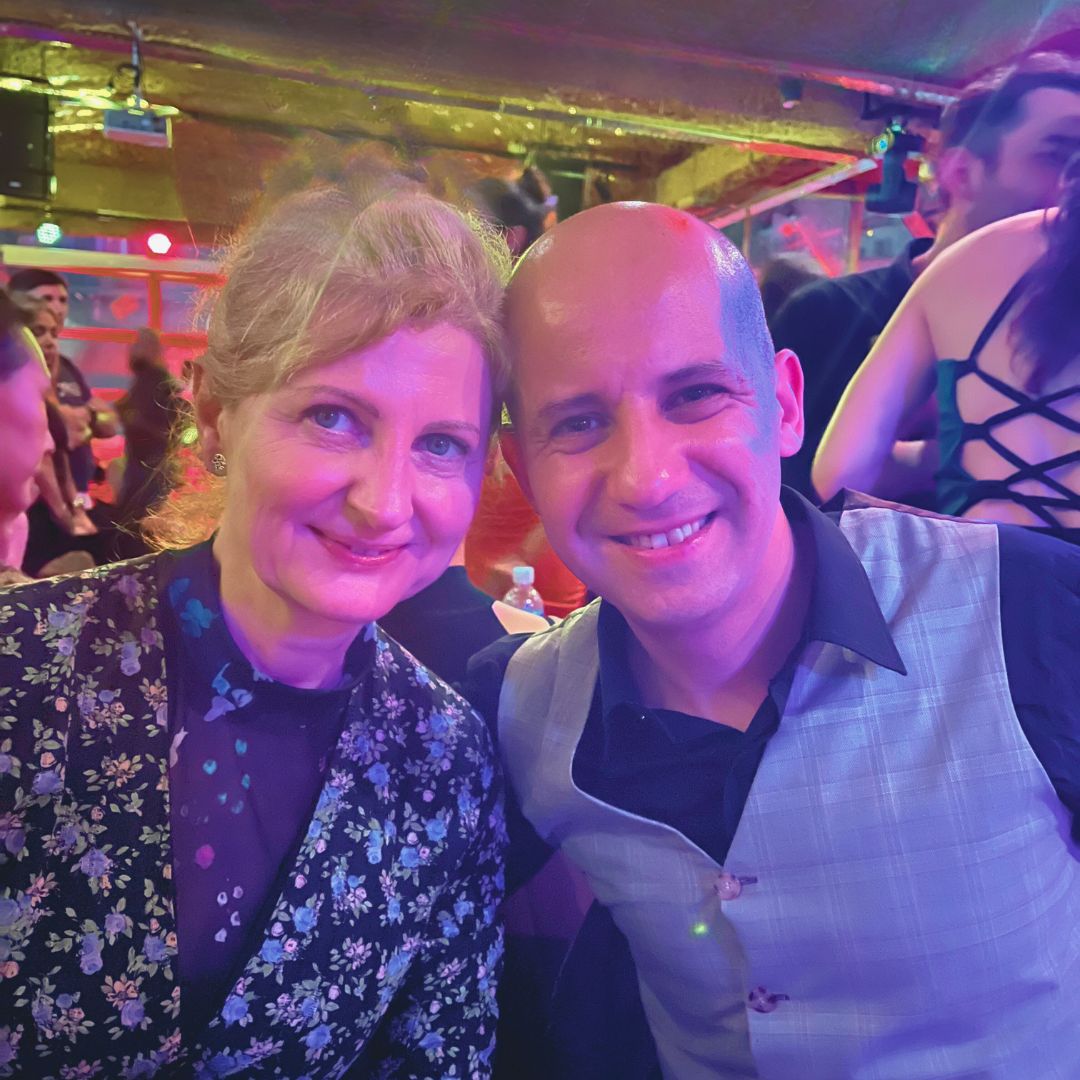 Nina Haus mit einem Tanzpartner in einer Milonga, im farbigen Licht des Saals.
