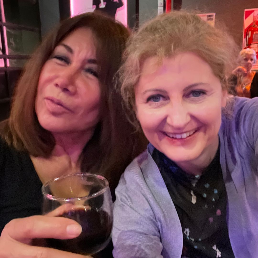 Nina Haus mit einer Freundin am Abend in einer Milonga, im rosafarbenen Licht des Saals.
